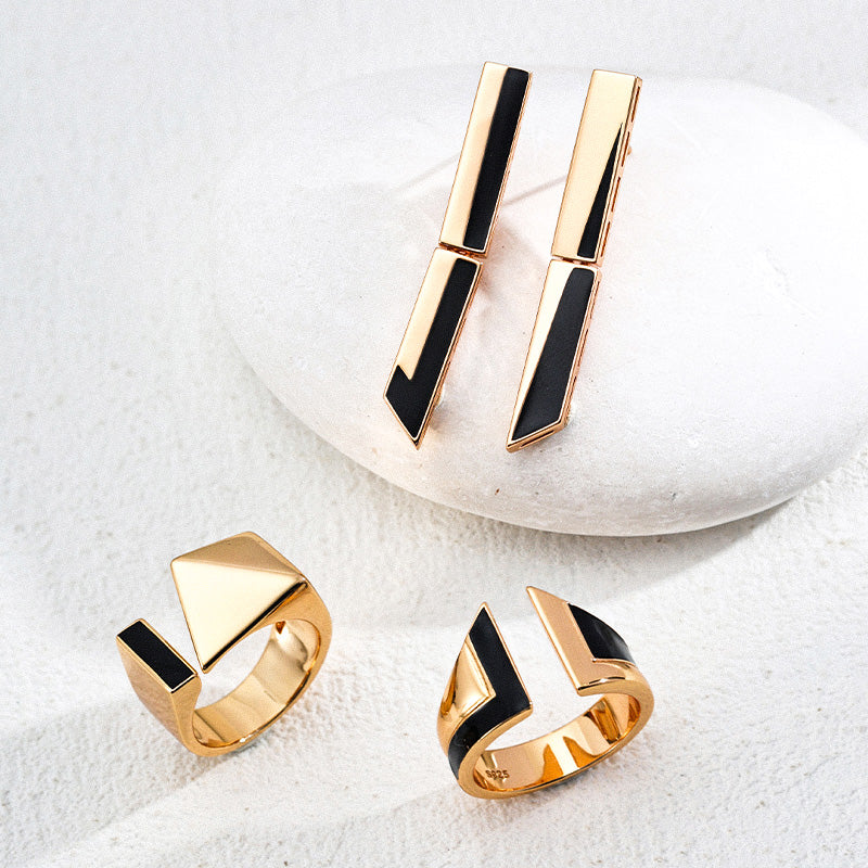 A coordinated jewelry set featuring long gold-plated geometric black enamel earrings alongside two matching architectural rings, showcasing high-polish S925 silver with sleek lines and a minimalist modern vibe.