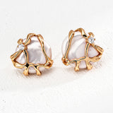 Close-up of two natural pearl earrings encased in abstract gold sculpted 925 silver, each adorned with a brilliant zircon for added sparkle.