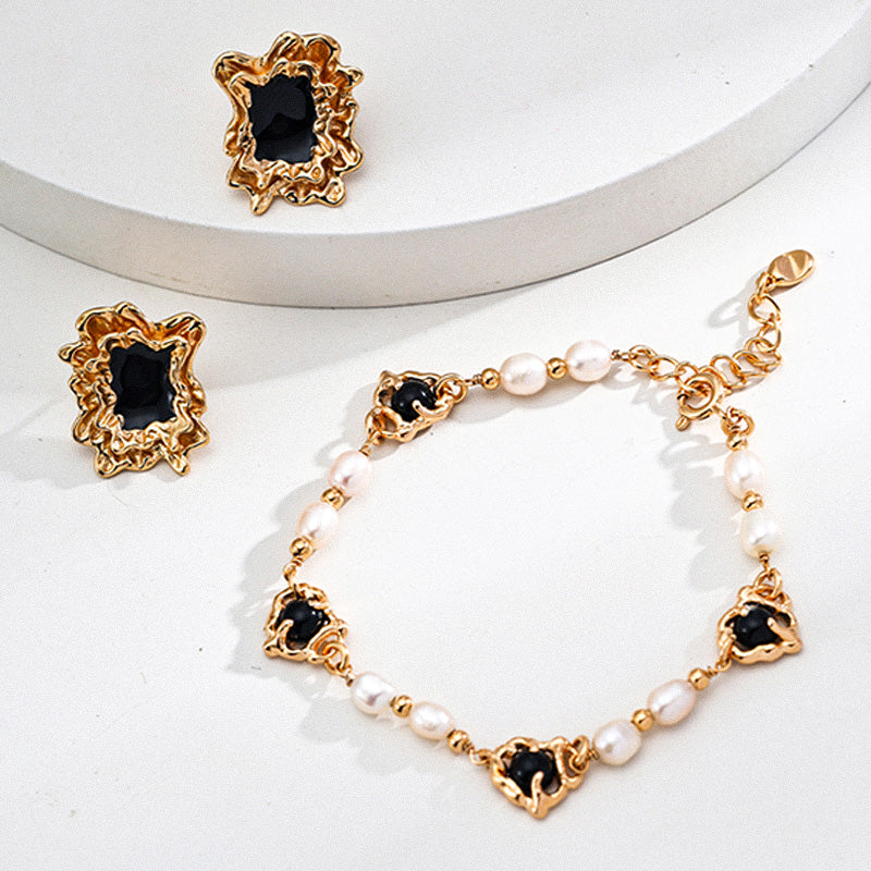 Statement bracelet featuring natural pearls and black onyx cabochons set in intricate S925 silver gold plating, photographed alongside bold matching earrings in a soft, minimal setting.