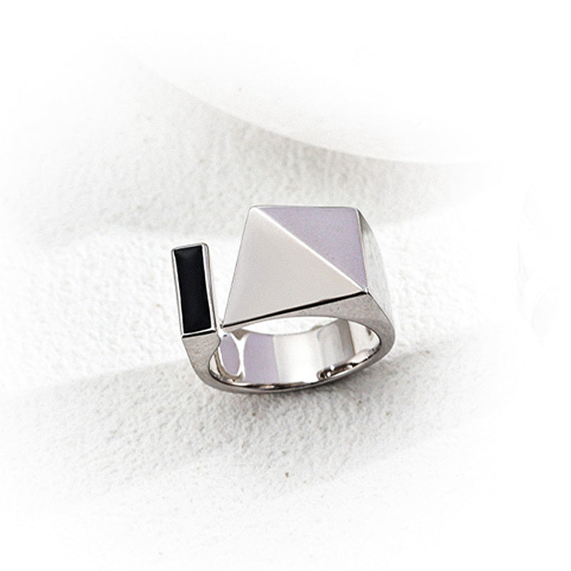 Close-up of the silver version of the S925 geometric open ring with a polished pyramid and a black enamel bar, resting on a textured white backdrop to highlight its modern, sculptural silhouette.
