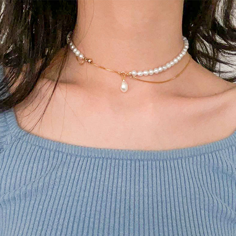 Choker-style double-wrap pearl necklace with a delicate drop charm, combining elegance and playful charm in one piece.