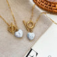 Two heart-shaped baroque pearl necklaces with gold OT clasps, displayed on beige fabric for a natural look.
