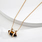 Zoomed-in view of the gold-framed tiger’s eye pendant on a delicate S925 gold-plated chain, resting on a white round ceramic prop to emphasize the gemstone's striped depth and polished cut.