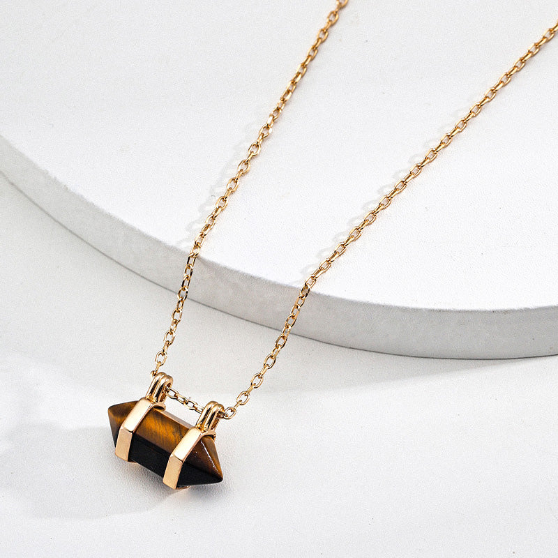 Zoomed-in view of the gold-framed tiger’s eye pendant on a delicate S925 gold-plated chain, resting on a white round ceramic prop to emphasize the gemstone's striped depth and polished cut.