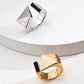 Side-by-side view of silver and gold variants of the S925 open ring, each featuring a geometric pyramid on one end and a black enamel rectangular inset on the other, arranged on layered ceramic surfaces.