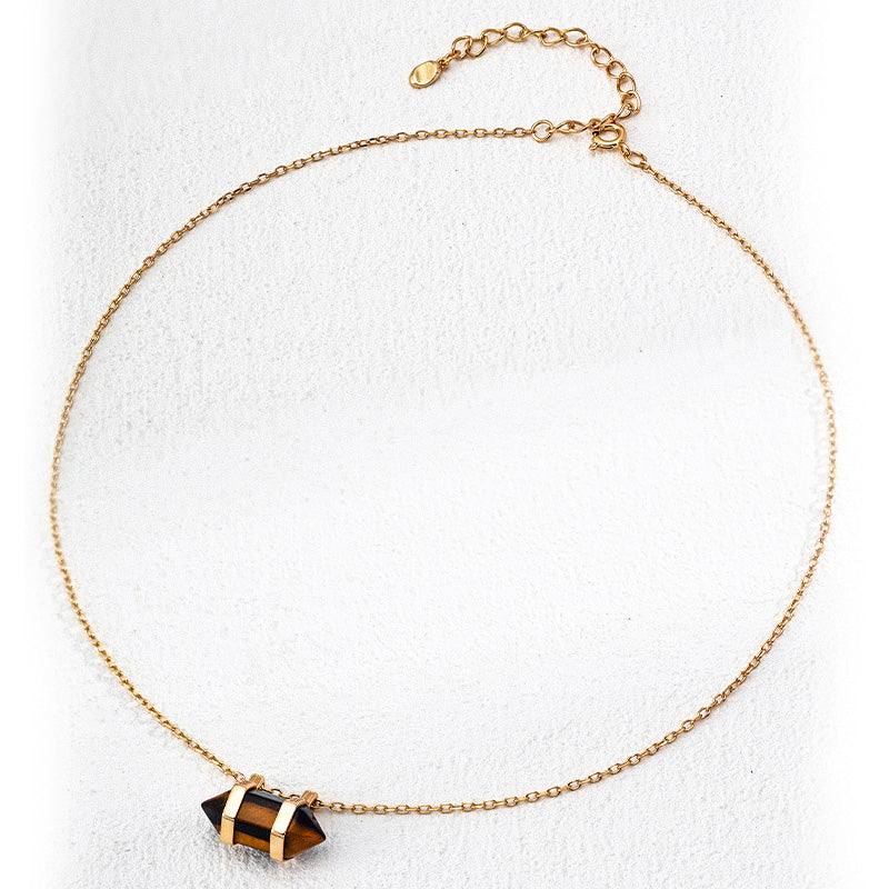 Flat-lay image of the S925 silver necklace featuring a faceted double-pointed tiger’s eye pendant held in a gold-plated frame, displayed on a soft white background with an adjustable clasp.