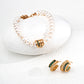 A pearl bracelet with gold and green zircon centerpiece paired with matching earrings, styled on a white stone background.
