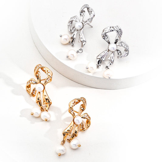 Elegant gold and silver ribbon bow earrings adorned with freshwater pearls, celebrating feminine charm and delicate craftsmanship.