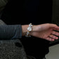 Close-up of a woman's wrist wearing a keshi baroque pearl bracelet with gold accents, styled with a dark knit blazer.