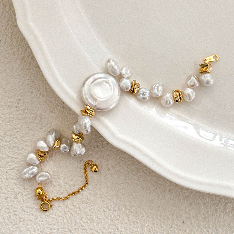Flat lay of Luminique’s keshi baroque pearl bracelet featuring a round central disc pearl, gold-plated silver clasp, and asymmetrical freshwater pearls.