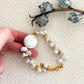 Hand holding a keshi baroque pearl bracelet with organic white pearls and 18K gold-plated elements, styled with a botanical accent.