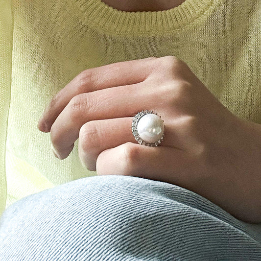 Model wearing the Mabe pearl halo ring by Luminique on finger, styled with soft knitwear to convey understated luxury.