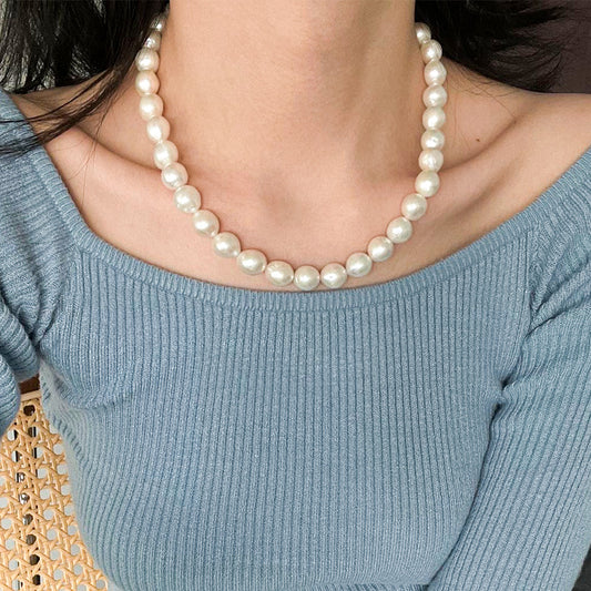 Woman wearing a classic Edison freshwater pearl necklace with a blue knit top — showcasing timeless femininity and everyday elegance.