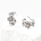 Detailed image of S925 sterling silver floral stud earrings, each bloom adorned with sparkling yellow zircon, placed on a textured white display.
