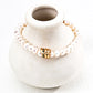 Natural freshwater pearl bracelet featuring a unique gold and green zircon buckle centerpiece, displayed on a ceramic vase.