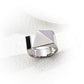 Close-up of the silver version of the S925 geometric open ring with a polished pyramid and a black enamel bar, resting on a textured white backdrop to highlight its modern, sculptural silhouette.