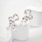 Charming silver ribbon bow earrings with luminous freshwater pearls, offering a graceful, vintage-inspired elegance.