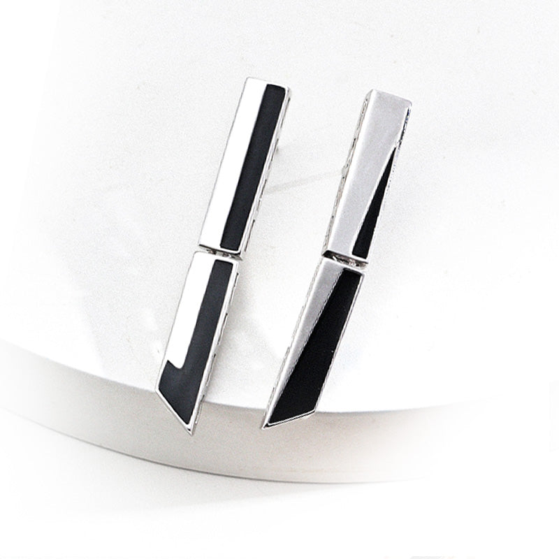 Pair of silver-tone S925 earrings with architectural geometry and black enamel striping, presented on a white matte platform for a crisp, minimalist presentation of contemporary design.