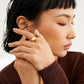 A model wearing the gold-tone S925 silver geometric enamel ring on her index finger, showing its bold contrast between glossy black enamel and minimalistic pyramid structure, exuding modern edge.