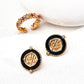 The gold-tone S925 zircon ring displayed next to round medallion-style earrings in black enamel and gold.