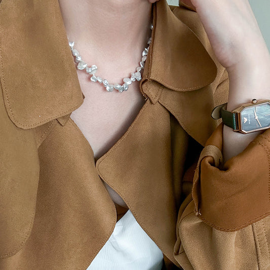 Woman wearing a white keshi freshwater pearl necklace, styled with a tan trench coat for an effortless statement look.