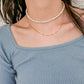 Minimalist two-layer pearl and gold chain necklace worn as a choker, offering a fresh take on classic pearl styling.
