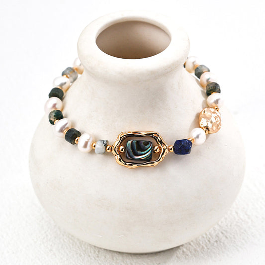 Artistic close-up of a S925 silver bracelet draped on a ceramic vase — designed with natural pearls, lapis lazuli, and a shimmering abalone shell centerpiece.