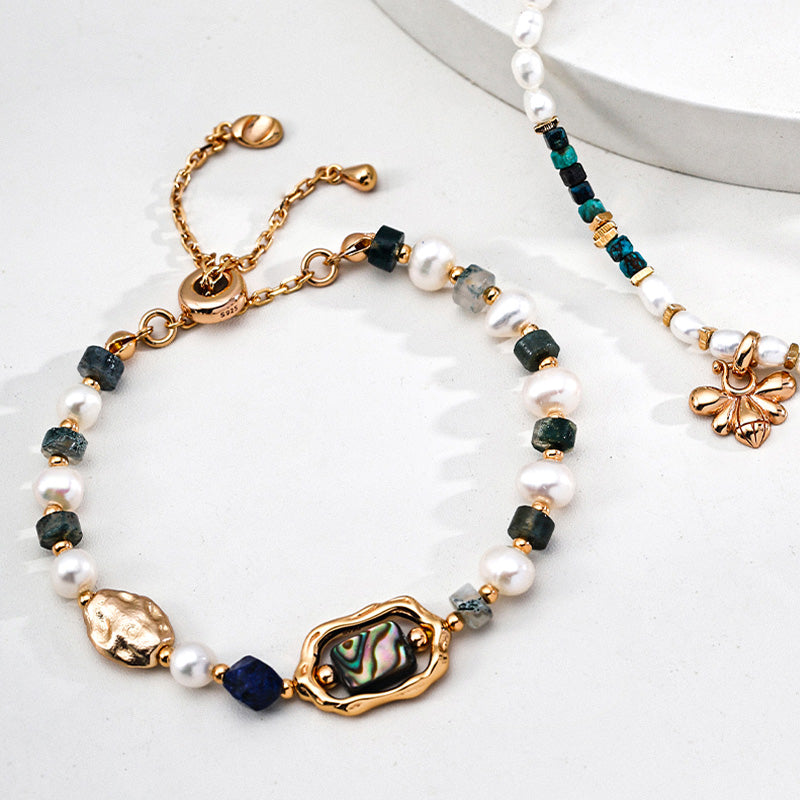 Layered bracelet styling featuring natural pearl, moss agate, and abalone in S925 silver — paired with a delicate bee charm, echoing connection and warmth.
