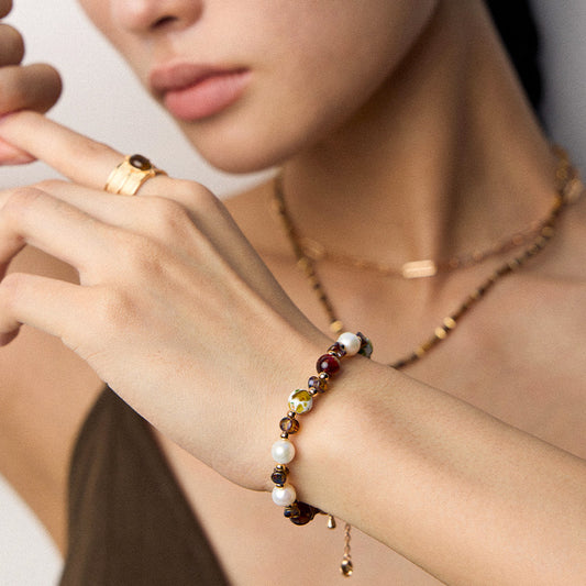 Styled shot of a model showcasing a vintage-style bracelet with pearl and shell beads — a statement of gentle strength and personal energy.